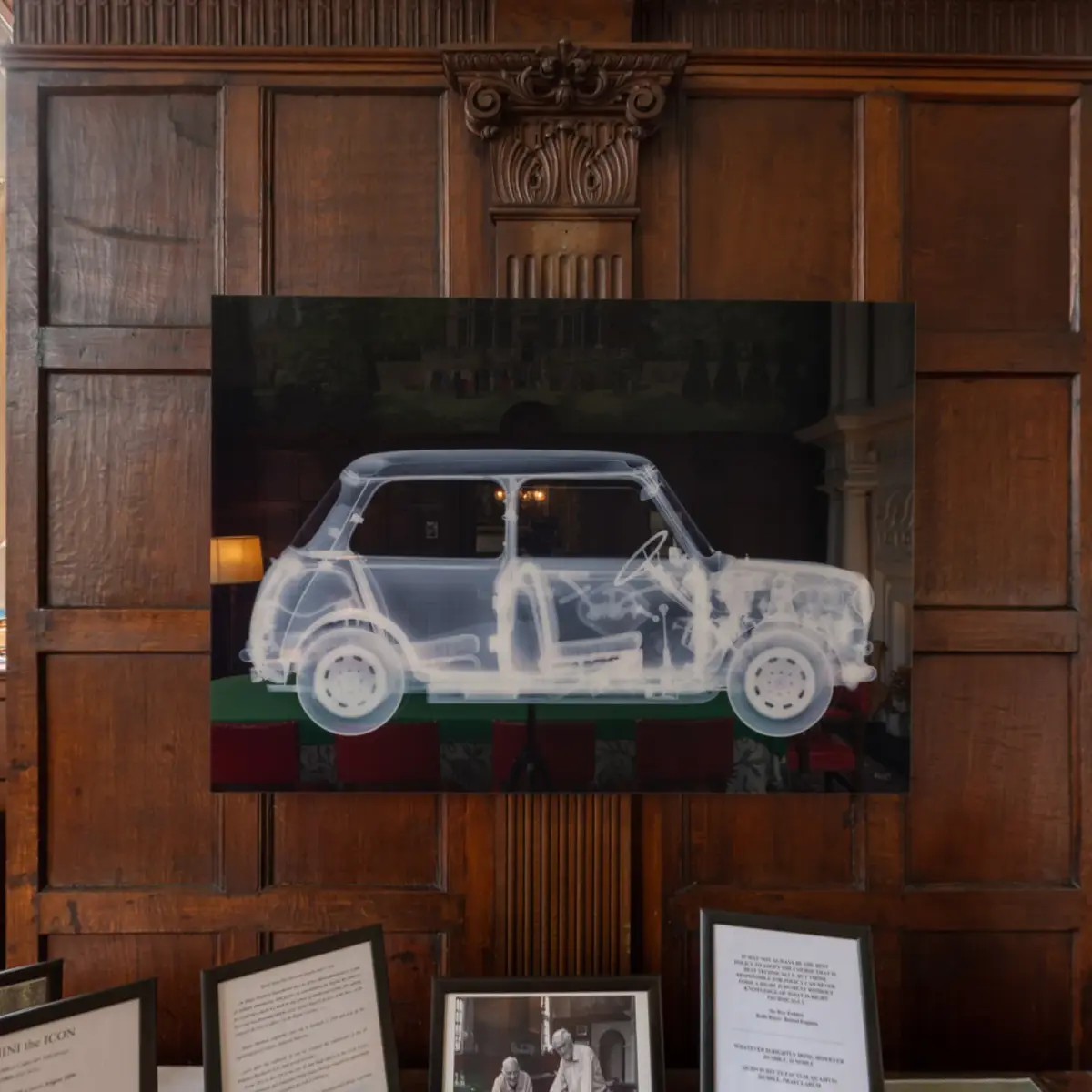 A panorama of the panelled dining room, leaded windows along one wall, a painted overmantel and framed drawings and photographs propped around the room